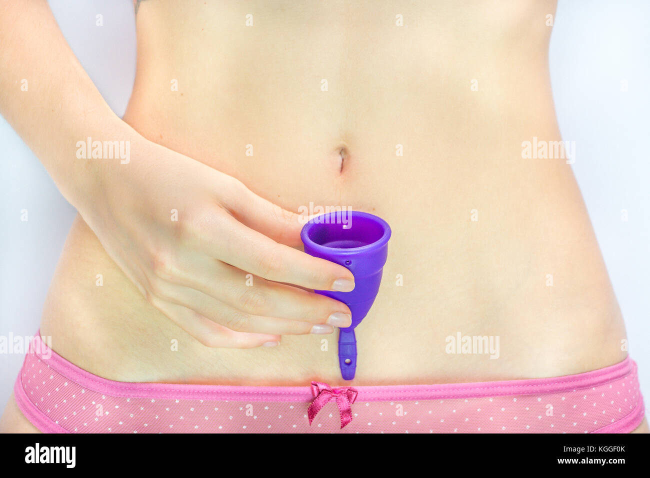 Junge Frau mit einem lila Menstruationstasse - weißer Hintergrund. Stockfoto