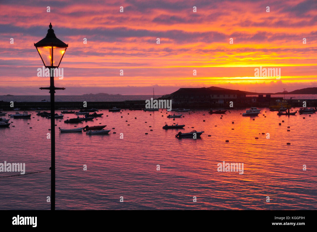 Sonnenuntergang über St Marys Hafen auf die Scilly-inseln, Lamp Post spiegelt die untergehende Sonne. Cornwall GROSSBRITANNIEN Stockfoto