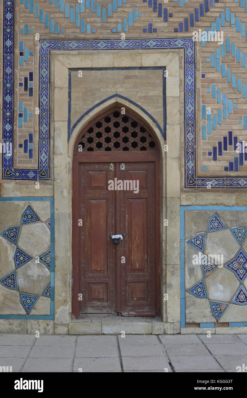 Die hölzerne Tür mit den dekorativen Fliesen auf dem Mausoleum in der Seidenstraße Stadt Turkestan, Kasachstan. Islamische geometrische Muster. Stockfoto