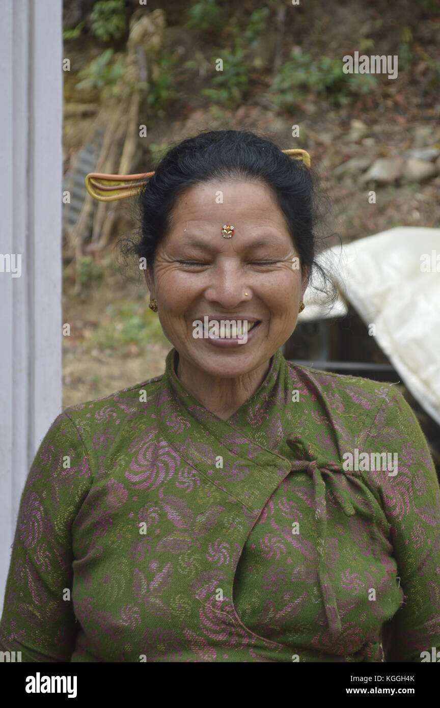 Alte nepalesische Dame mit einem schönen Lächeln und geschlossenen Augen in einem kleinen Bergdorf im Himalaya, Panauti, Nepal. Kamm im Haar, traditionelle Kleidung, Bindi Stockfoto