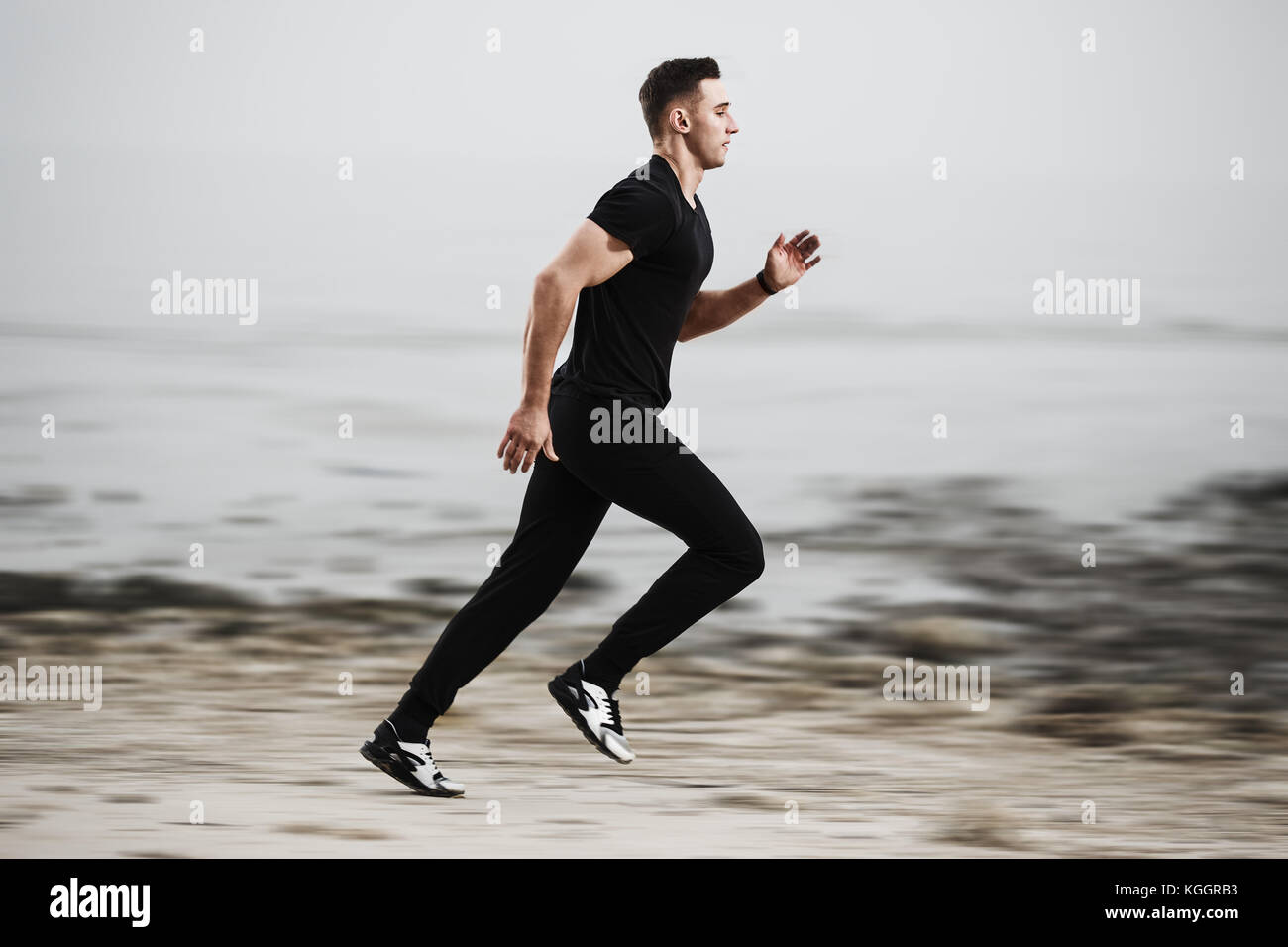 Athletischer Mann von der felsigen Küste Küste läuft. Stockfoto