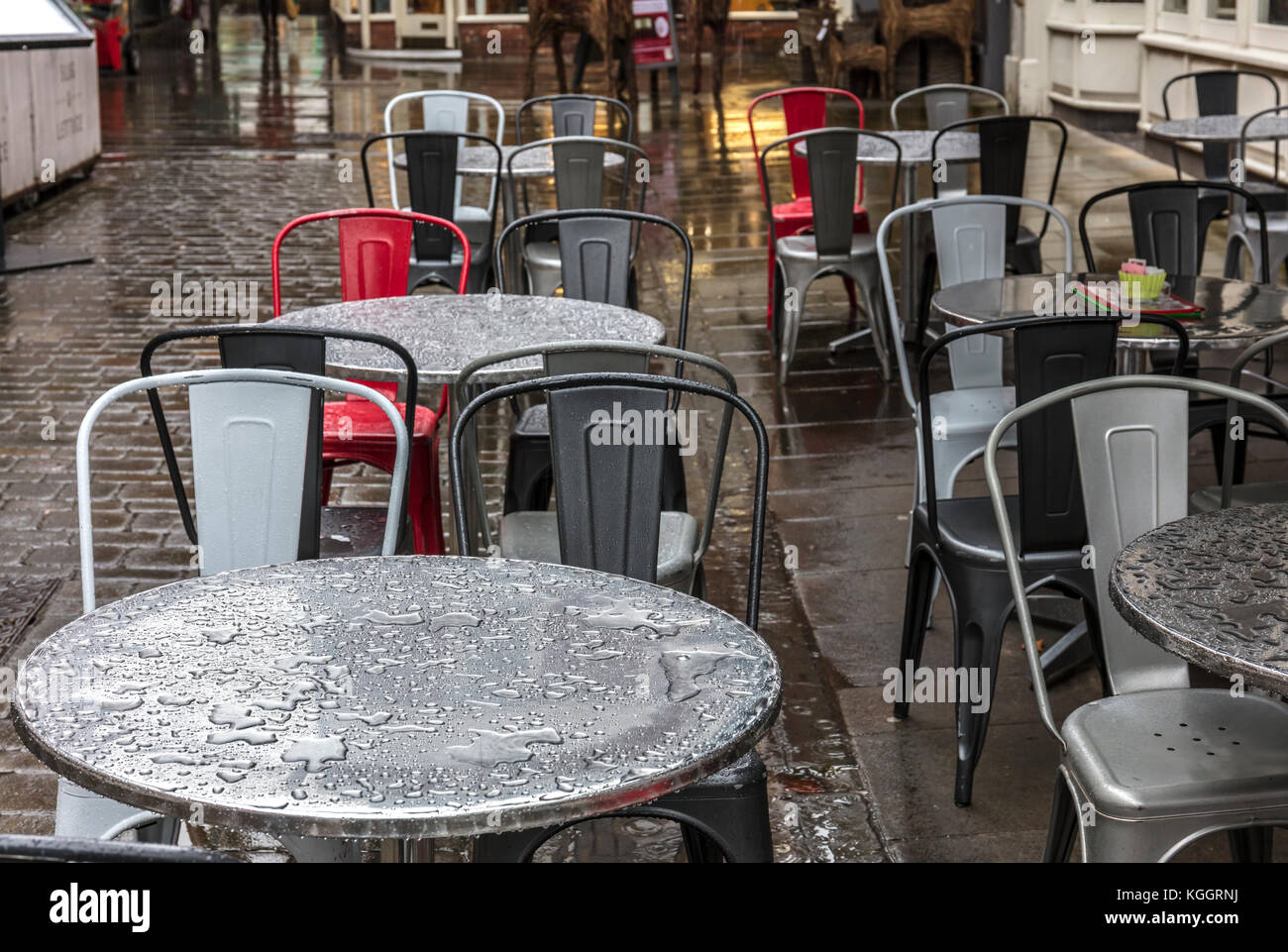 Nasse cafe Tabellen, roten Stuhl und Kopfsteinpflaster, Winchester Stockfoto