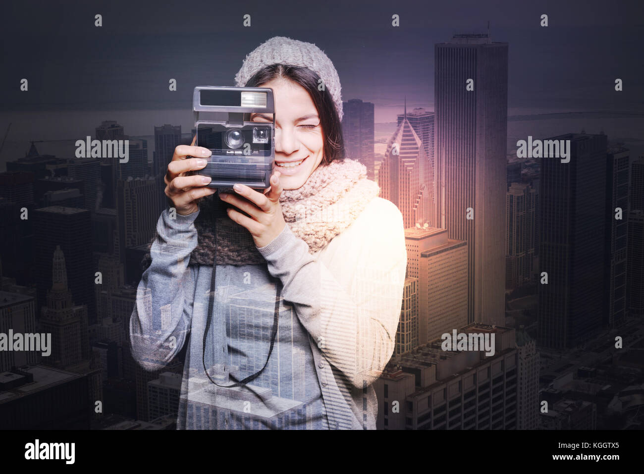 Fangen Momente. schöne glückliche junge Frau in eine warme Strickmütze lächelnd, während Sie ein Foto mit Hilfe eines Instant Foto Kamera Stockfoto