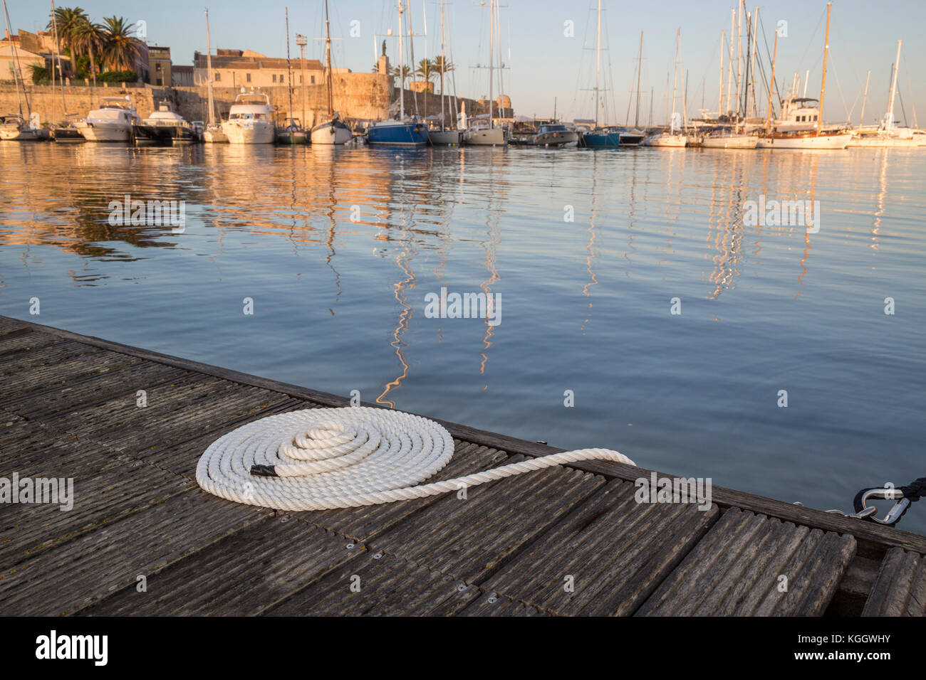 Ordentlich aufgewickelt, weiß Seil auf einem Steg mit Yachten im Hintergrund Stockfoto