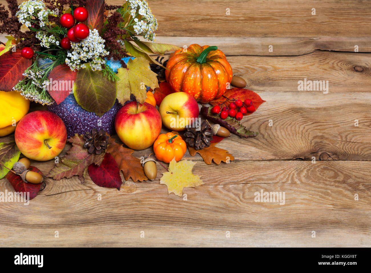 Thanksgiving Tabelle Mittelstück mit weißen Blumen in der Vase, Kürbisse, Äpfel, Kegel, Eicheln und buntes Herbstlaub, kopieren Raum Stockfoto