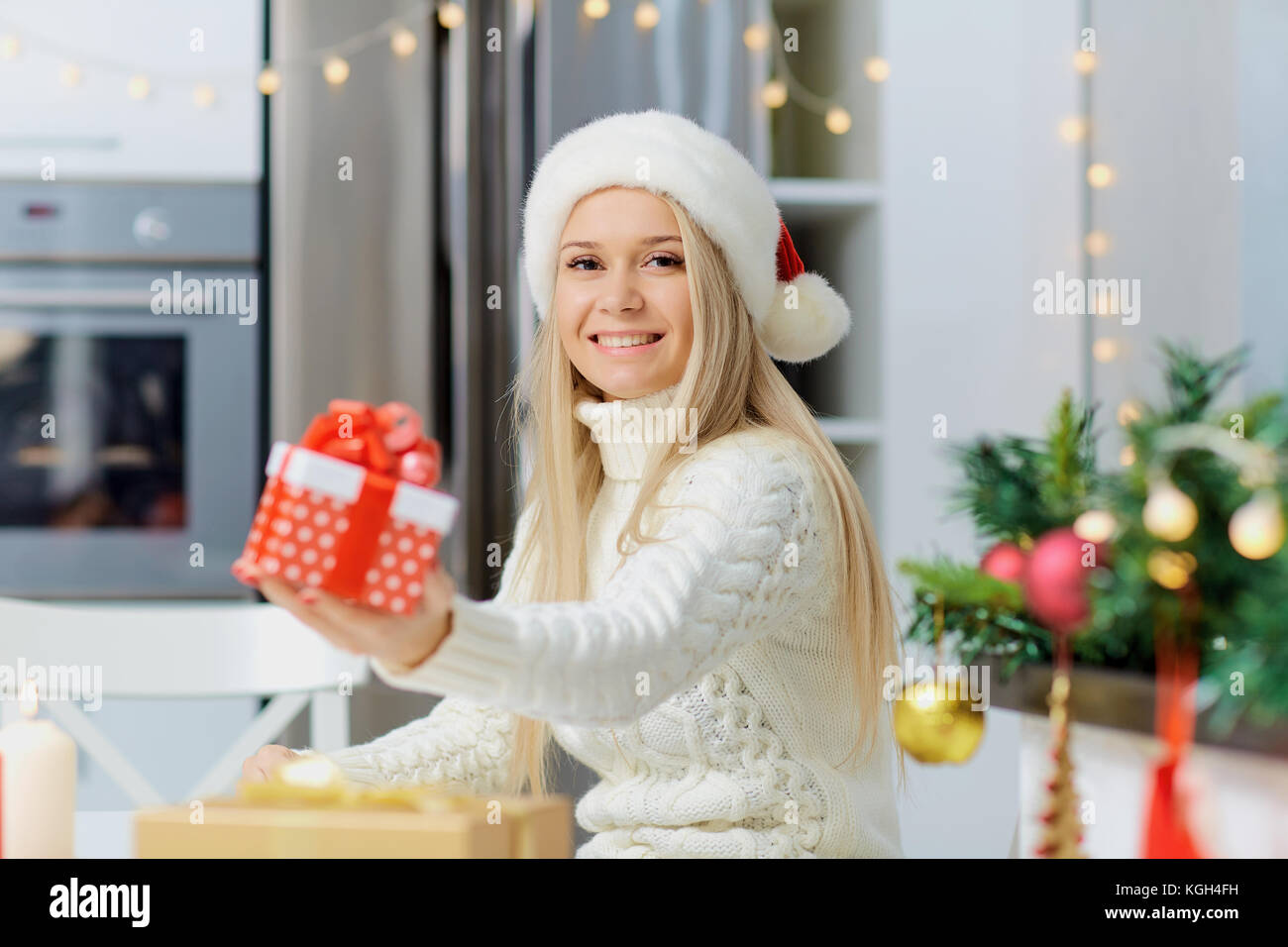 Ein Mädchen in einem santa claus Hut mit einem Geschenk in der Hand für christma Stockfoto