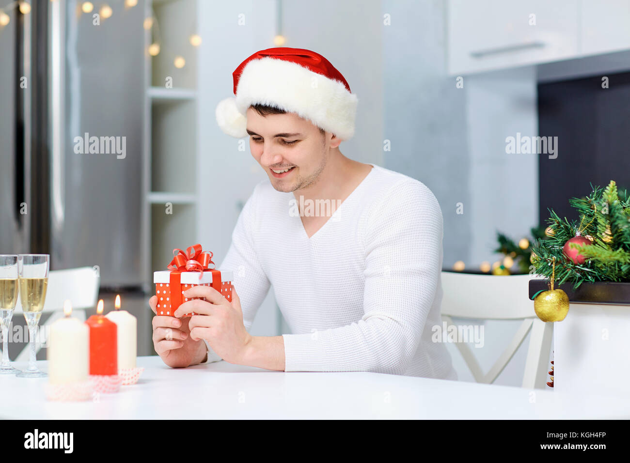 Ein Kerl in einem santa claus Hut mit einem Geschenk an einem Tisch in einem Weihnachten Stockfoto