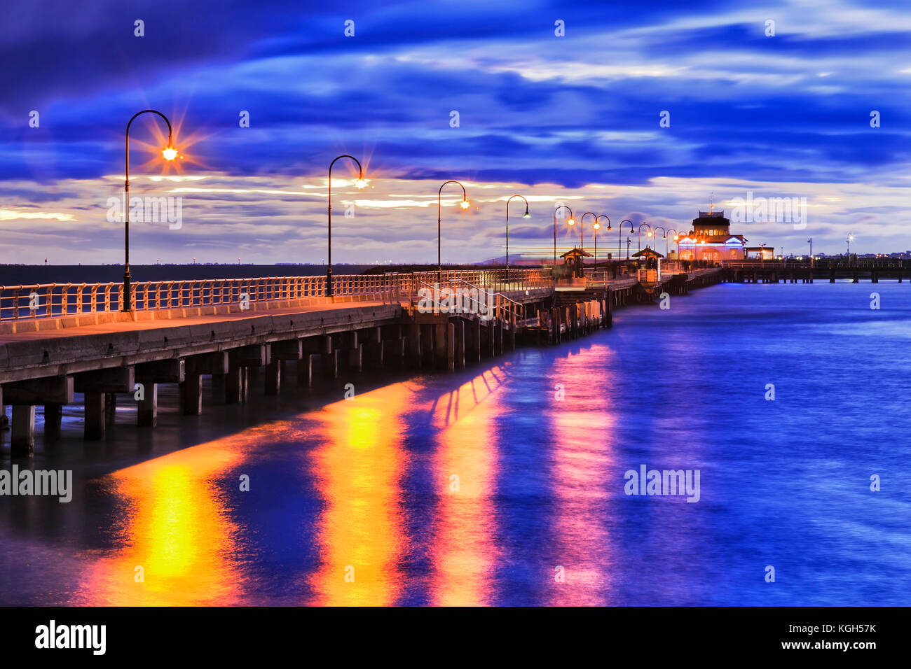 Stürmische Sonnenuntergang am Port Philip Bay um St Kilda Strand historischen Fachwerkhäuser Bootsanleger mit Straße Licht Beleuchtung im blauen Wasser der Bucht zu reflektieren. Melbourne Stockfoto