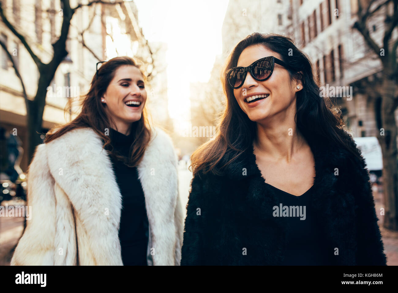 Zwei Frauen in warme Kleidung zu Fuß auf der Straße der Stadt. Lächelnd weibliche Freunde draußen in der Stadt an einem Wintertag. Stockfoto