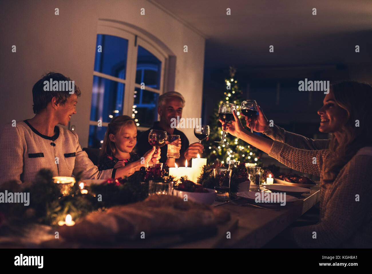 Drei generation Familie Weihnachten gemeinsam das Abendessen zu Hause. Erweiterte Familie toasten Wein zum Weihnachtsessen. Stockfoto