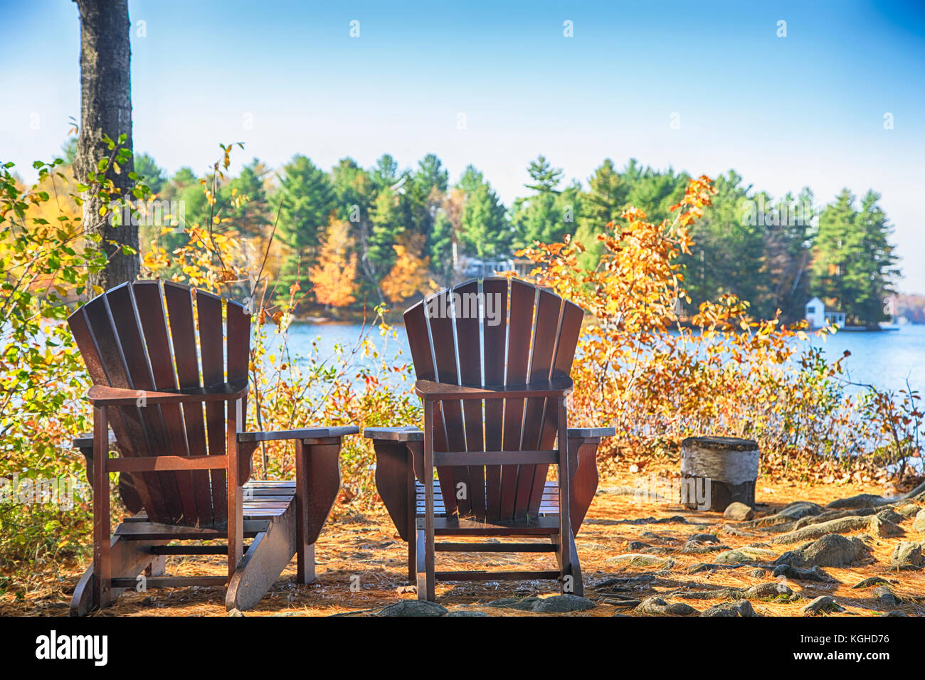 Zwei Muskoka Stühle auf einem Holz Dock an einem blauen See Stockfoto