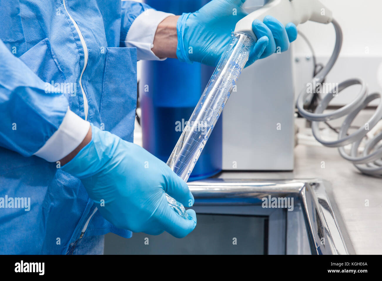 Wissenschaftler füllen ein Messzylinder mit destilliertem Wasser bei Labor Stockfoto