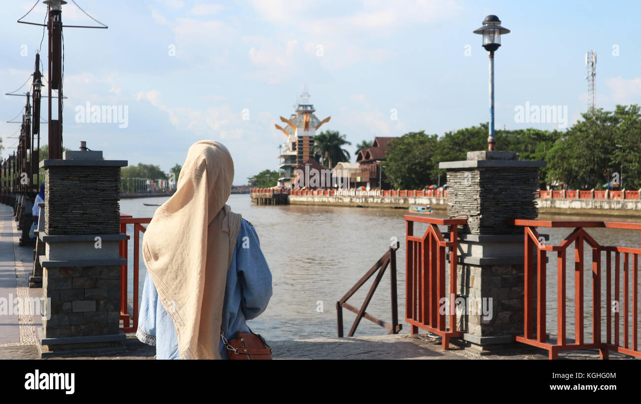 Junge Frau mit Kopftuch, allein auf Port/Fluss, Blick Richtung Wasser Stockfoto