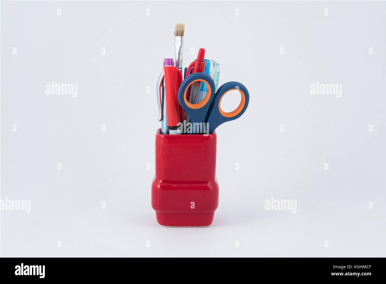 Einige Stifte, Pinsel und Schere in einem roten Stifthalter. Stockfoto