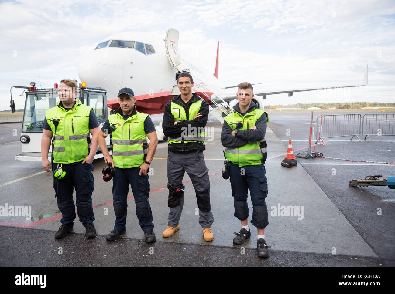 Im Team mit gekreuzten Armen stehend gegen Flugzeug Stockfoto