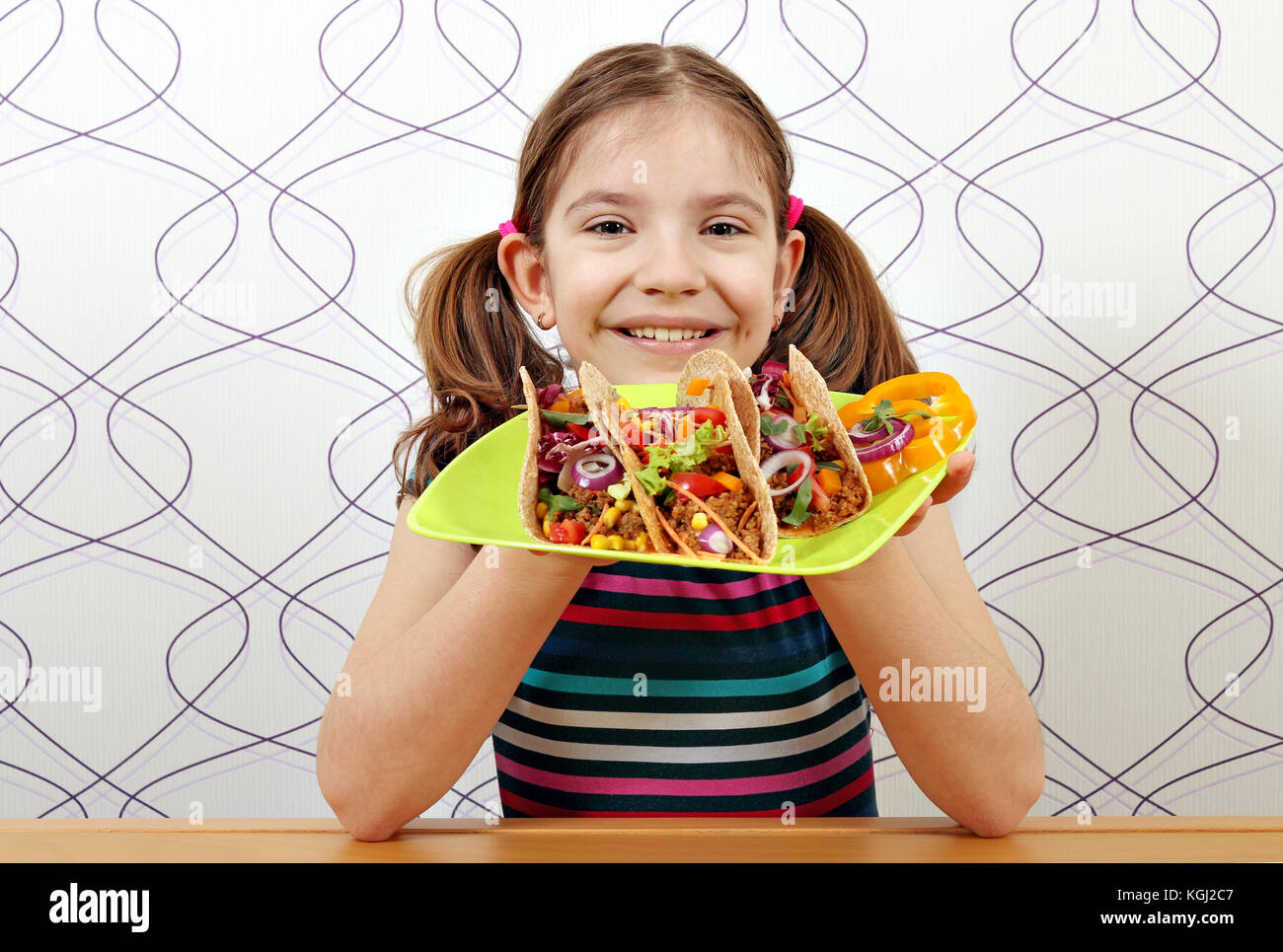 Glückliche kleine Mädchen mit Tacos für Mittagessen Stockfoto