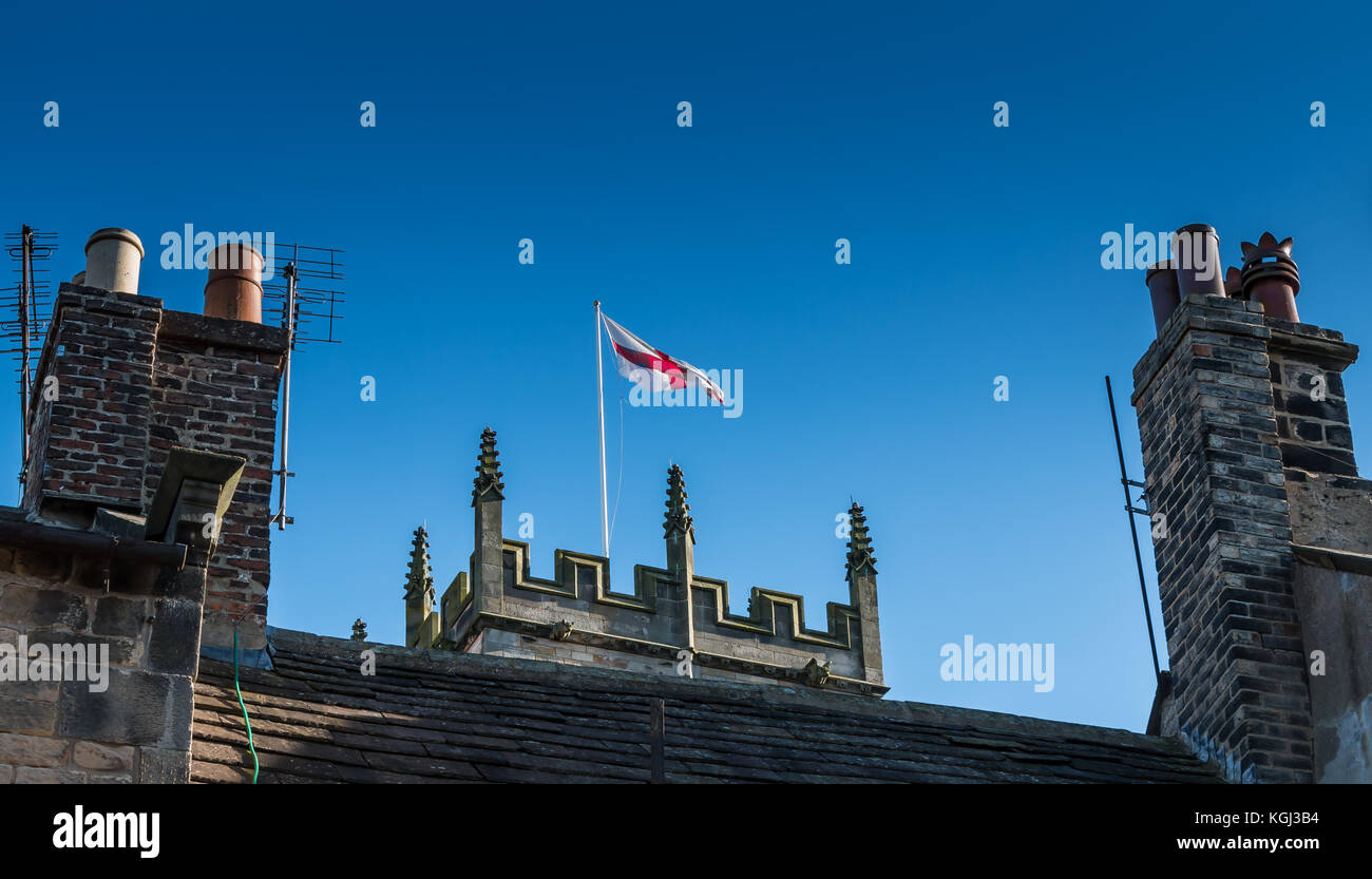 England Flagge Kreuz von St. George auf einem Kirchturm zwischen zwei Schornsteine unter einem klaren blauen Himmel bei Barnard Castle, Teesdale, North East England, Großbritannien Stockfoto