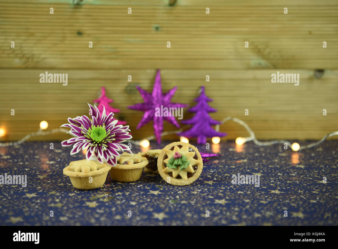 Weihnachten essen Fotografie Bild des traditionellen englischen mince pies mit winter blumen Christbaumschmuck und Lichterketten im Hintergrund glitter Stockfoto