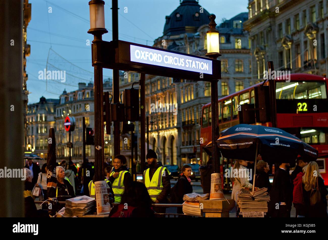 Männer verteilen Evening Standard an Weihnachtseinkäufer vor der U-Bahnstation Oxford Circus Stockfoto