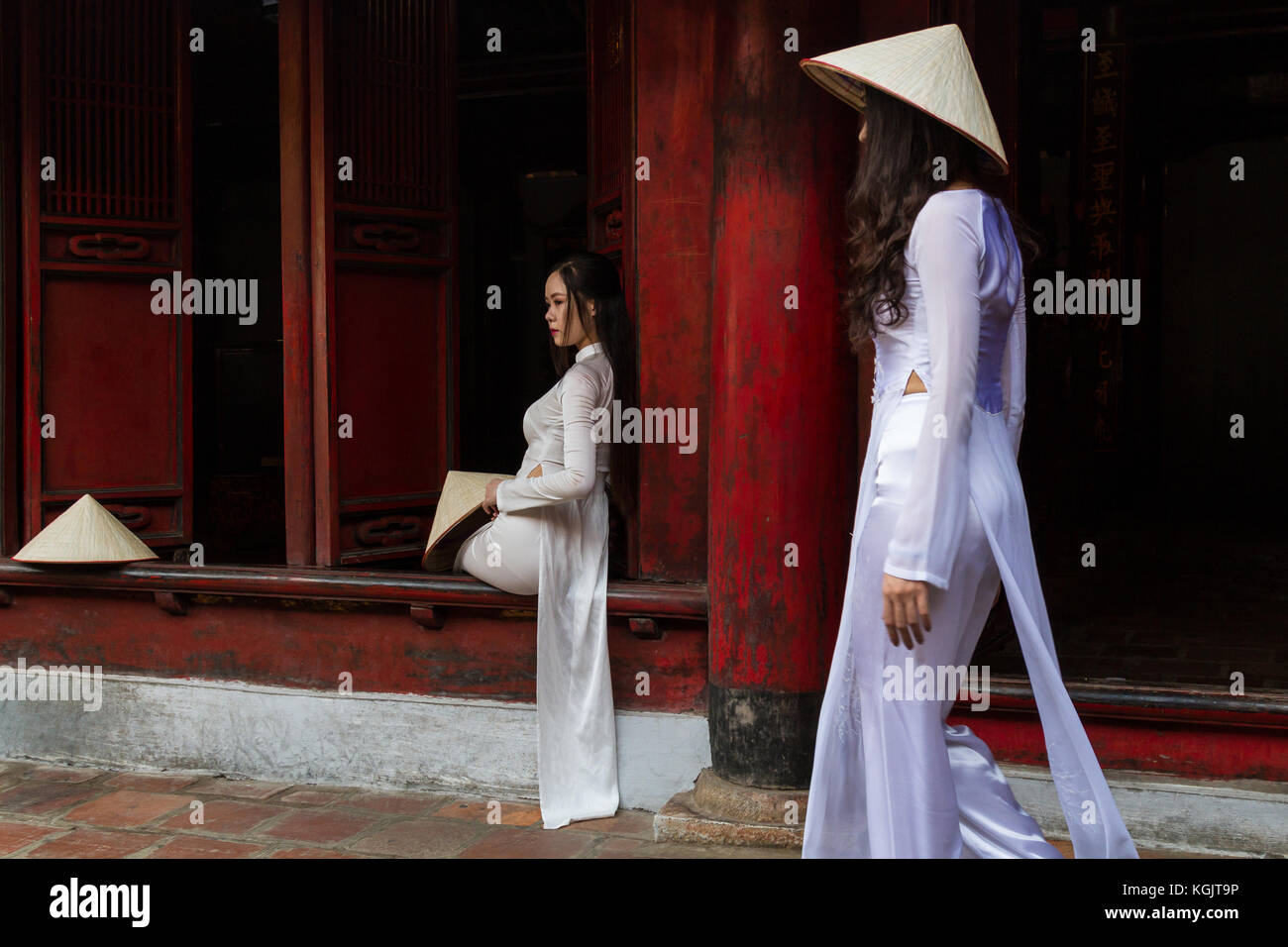 Junge vietnamesische Frauen, die die traditionelle Kleidung Ao Dai und der Konischen hat nicht La Lage; Tempel der Literatur in Hanoi, Vietnam Stockfoto