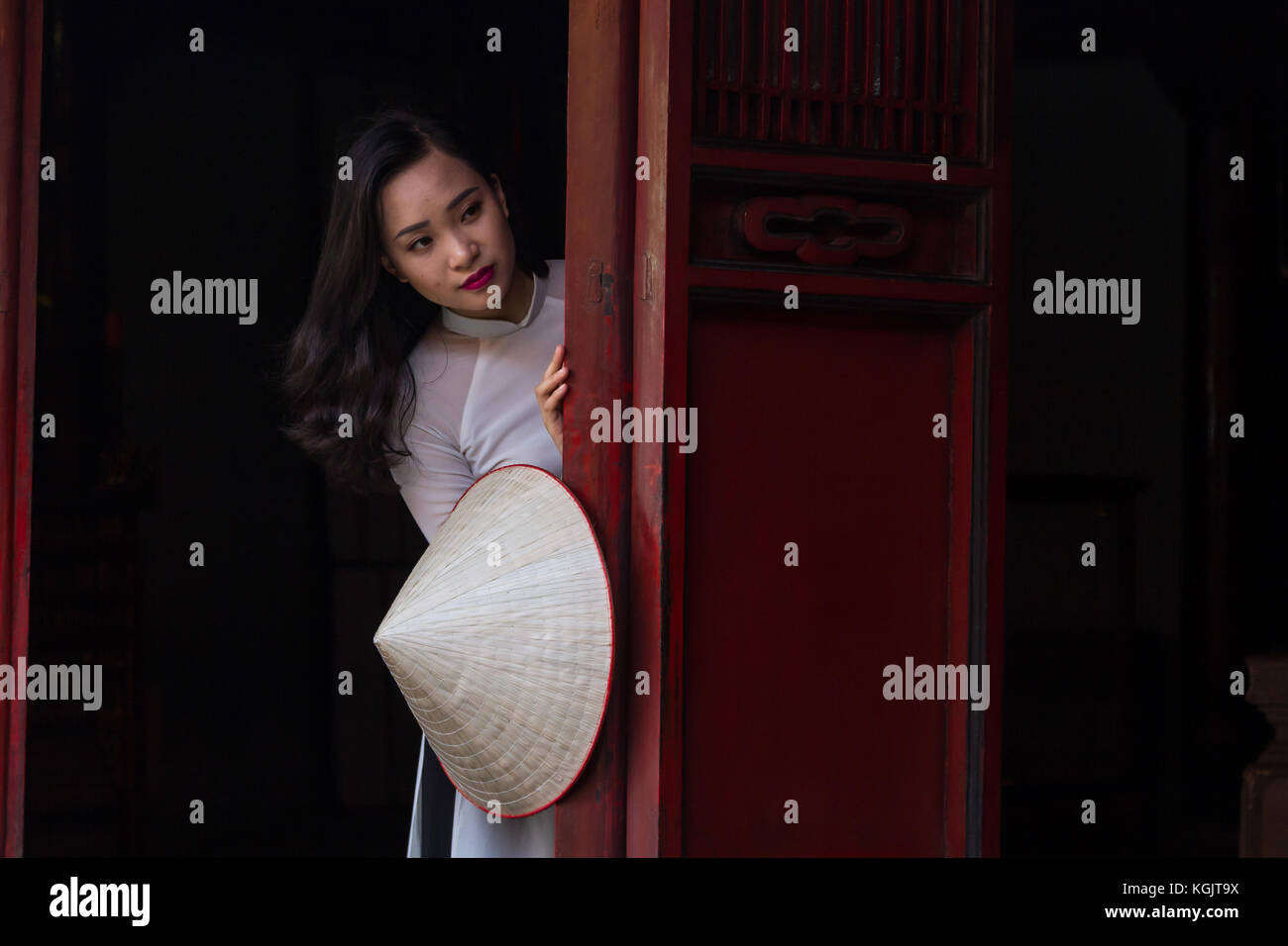 Eine junge Vietnamesin tragen die traditionelle Kleidung Ao Dai und der Konischen hat nicht La Lage; Tempel der Literatur in Hanoi, Vietnam Stockfoto