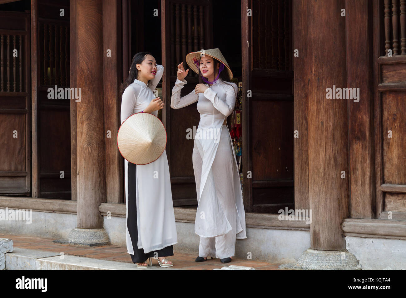 Junge vietnamesische Frauen, die die traditionelle Kleidung Ao Dai und der Konischen hat nicht La Lage; Tempel der Literatur in Hanoi, Vietnam Stockfoto