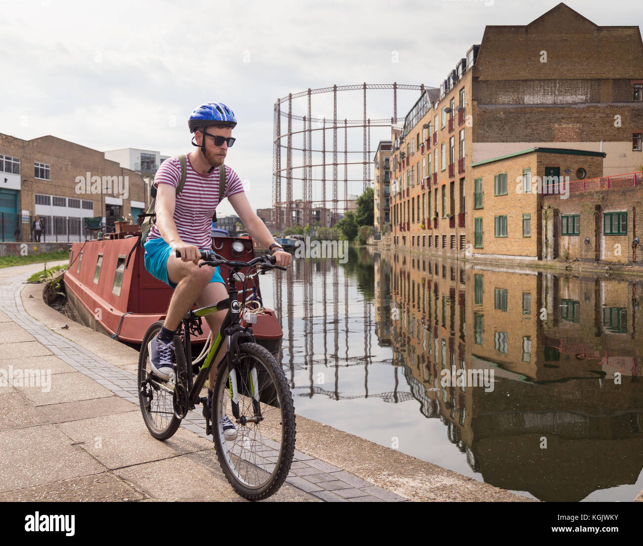 Junge Mann in weißem T-Shirt und Shorts Zyklen auf dem leinpfad von Regent's Canal im Sommer in Hackney, East London, UK. Stockfoto