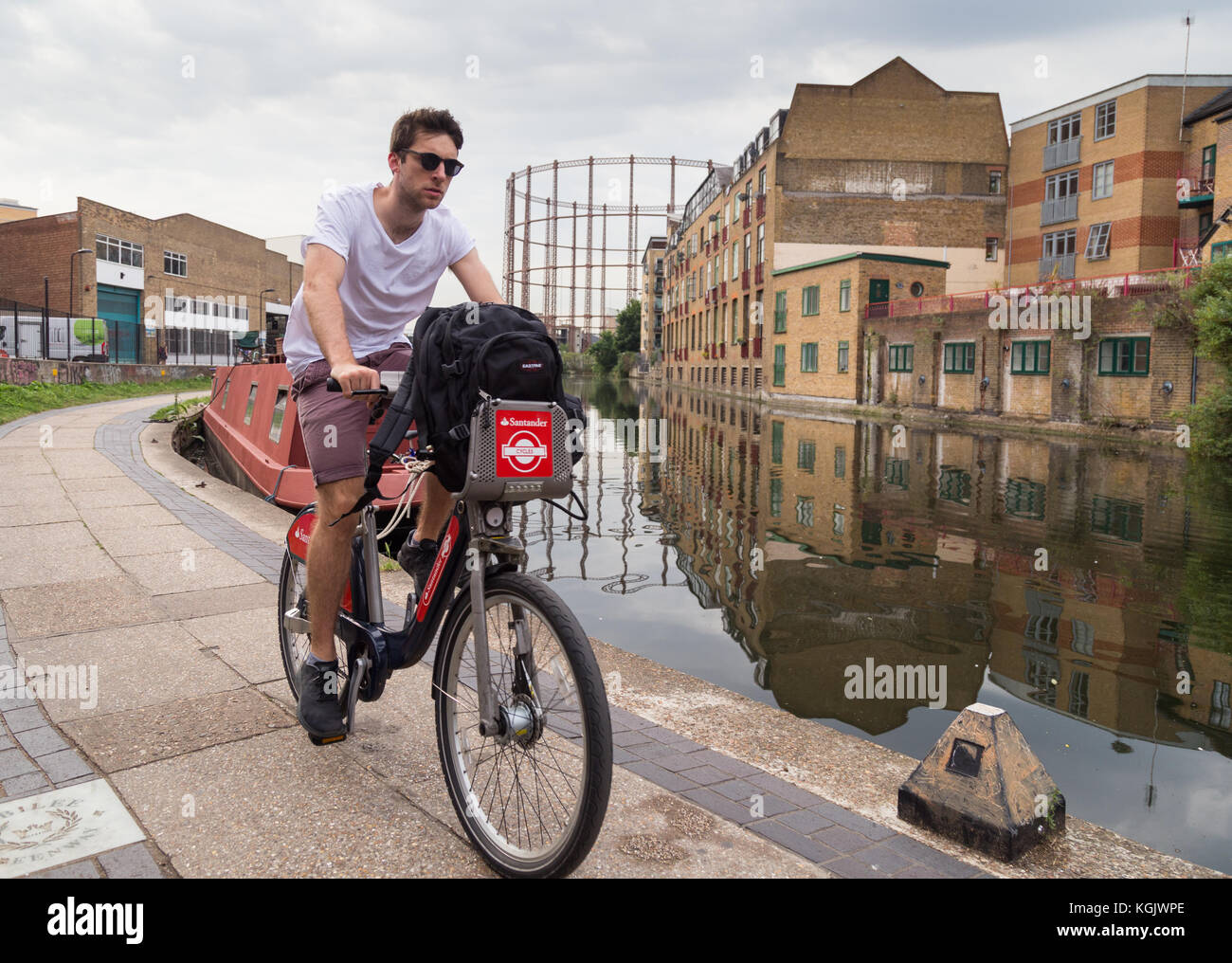 Junger Mann im Sommer T-Shirt und Shorts auf einem Fahrrad die Santander Zyklen auf dem leinpfad von Regent's Canal in Hackney, East London, UK. Stockfoto