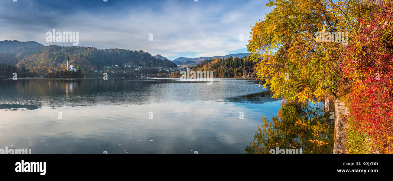 Bled, Slowenien - Panoramablick auf die schönen Herbstfarben am Bleder See mit Wallfahrtskirche Mariä Himmelfahrt und Bäumen Stockfoto