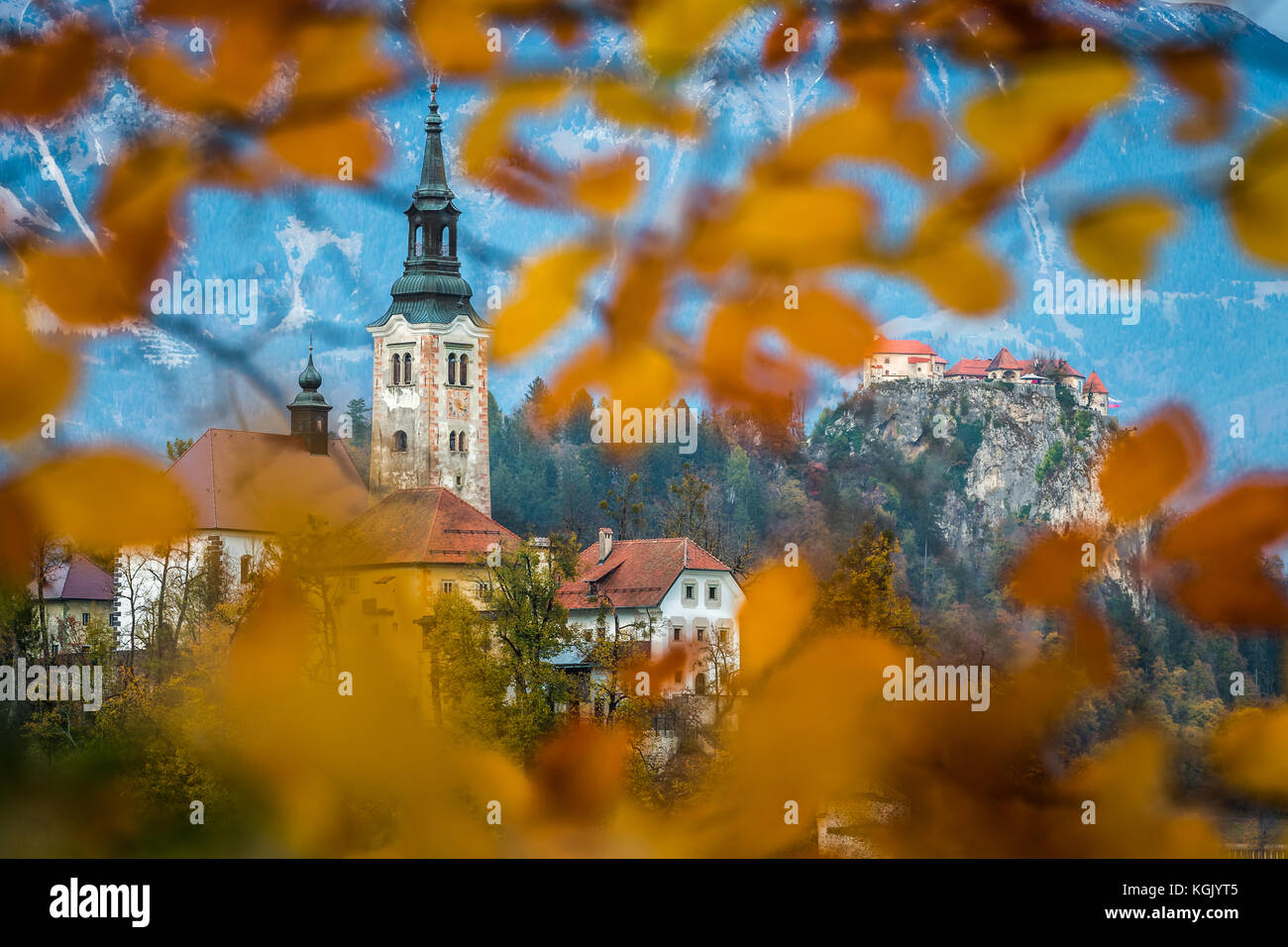 Bled, Slowenien - Schöne Herbstlaub gerahmte Wallfahrtskirche Mariä Himmelfahrt mit Schloss Bled und Julischen Alpen im Hintergrund Stockfoto
