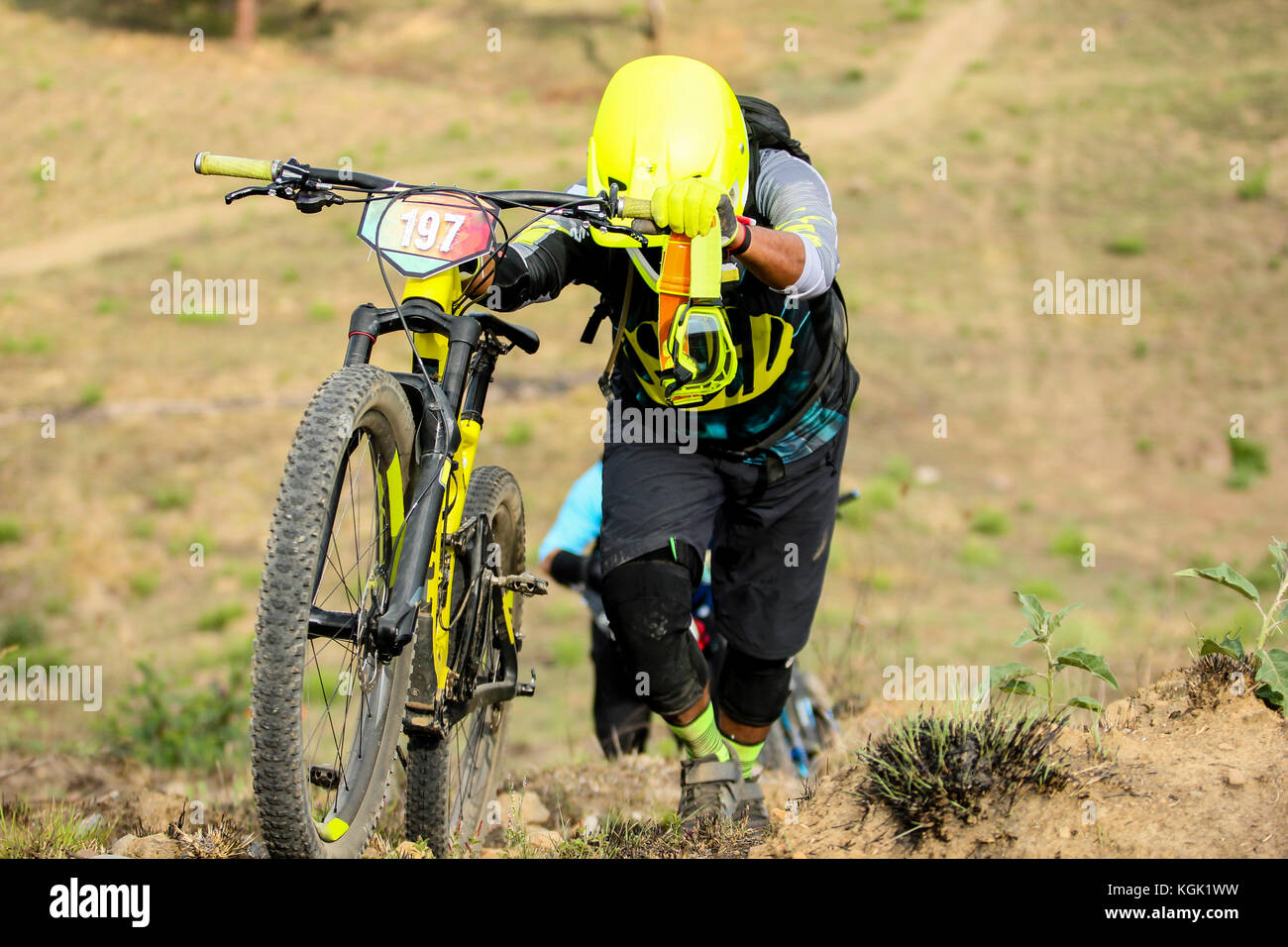 Horizontale Foto einer enduro Biker sein Fahrrad bergauf ziehen während eines Rennens Stockfoto
