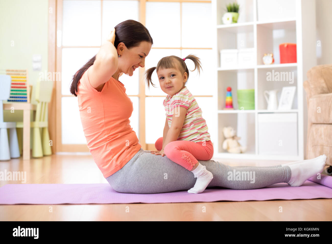Mutter und Kind Tochter sind in Fitness, Yoga, Übung zu Hause. Kind und Frau swing drücken Sie auf Magen. Stockfoto
