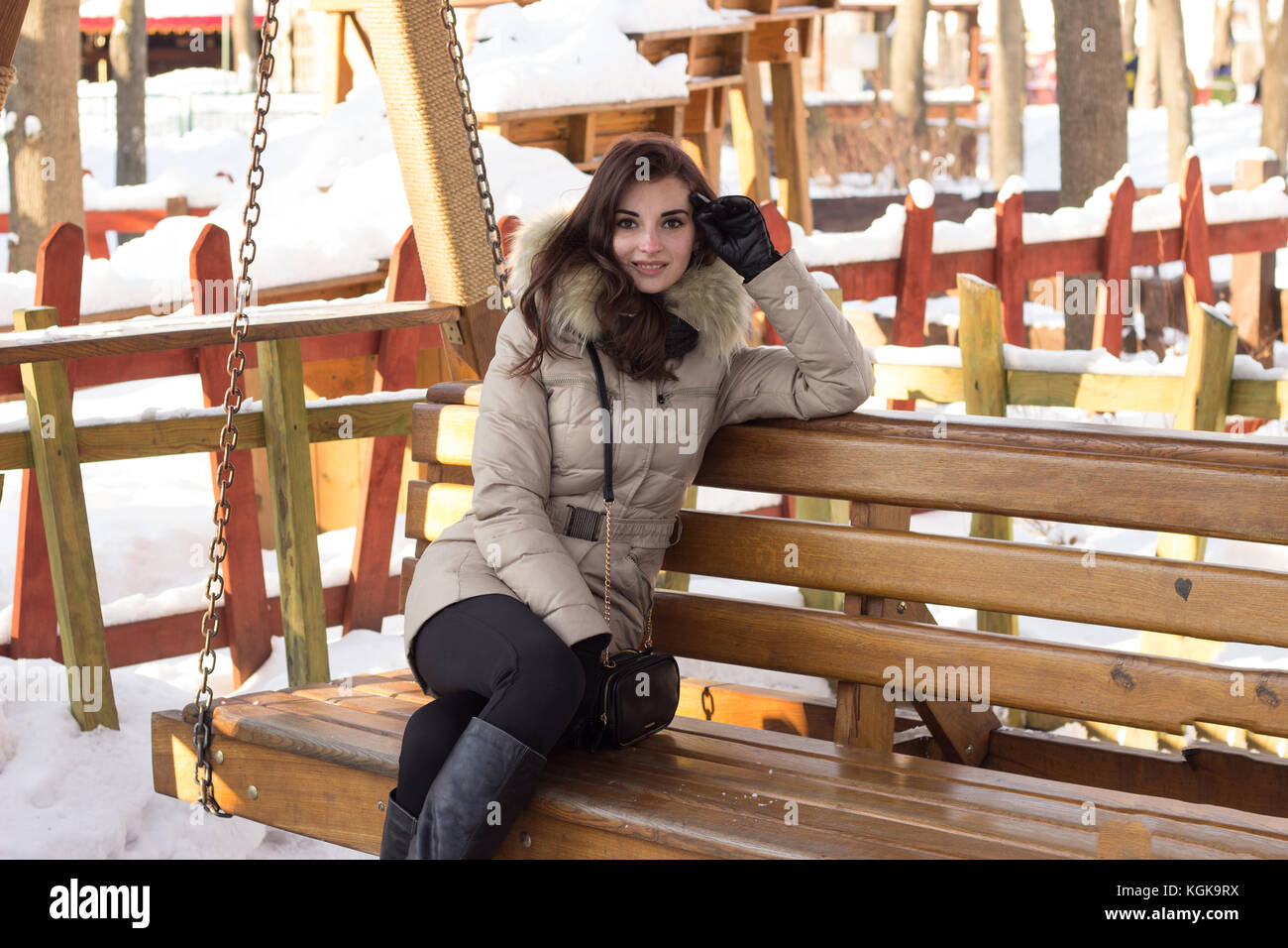 Junge Frau in Winter Park sitzt auf der Bank Stockfoto