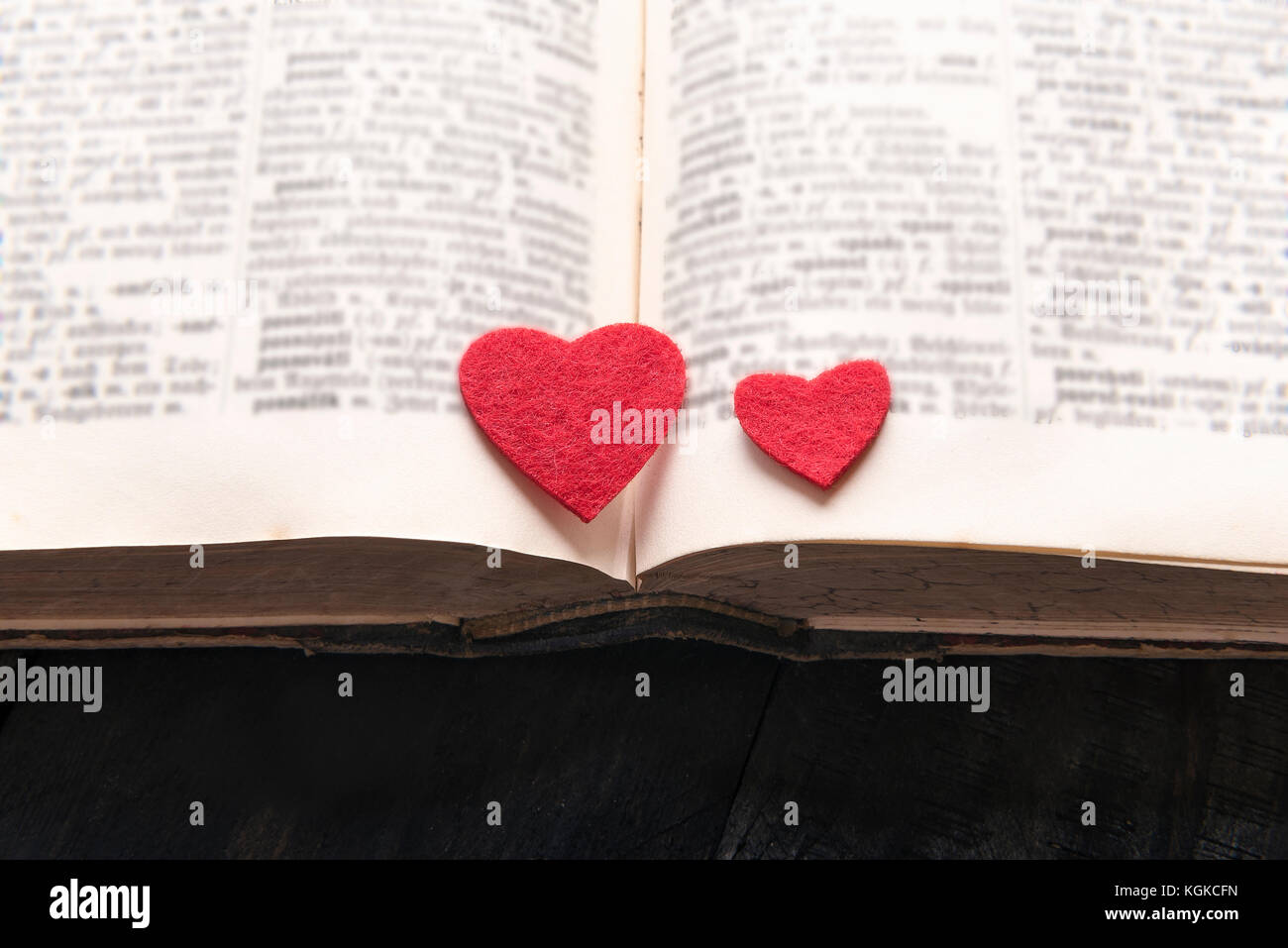 Close-up Bild mit zwei roten Herzen auf einem alten Buch öffnen platziert, auf einem Holztisch. ein Konzept für das Lesen, Lernen, Bildung oder für eine Liebesgeschichte, Roma Stockfoto