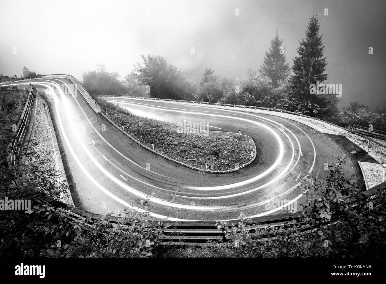 Gebirgsstrasse mit Auto leuchtet. nebliges Wetter und geringer Sichtweite. Alpen, Slowenien. Stockfoto