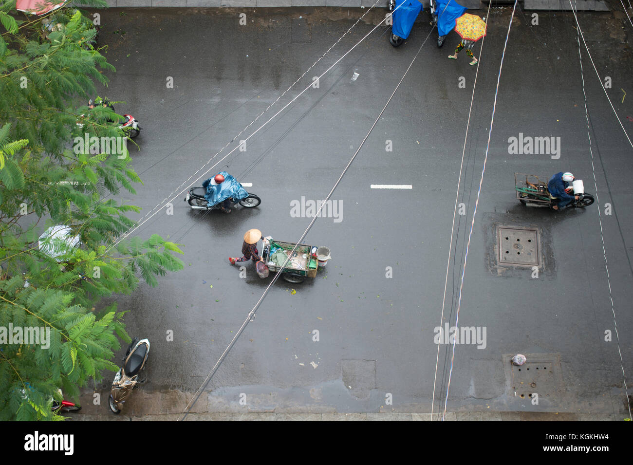 Luftaufnahme von einen Menschen auf den Roller und ein Verkäufer mit typischen vietnamesischen konischen Hüten und seine Barrow Spaziergänge durch die Straßen von Hanoi in Vietnam duri Stockfoto