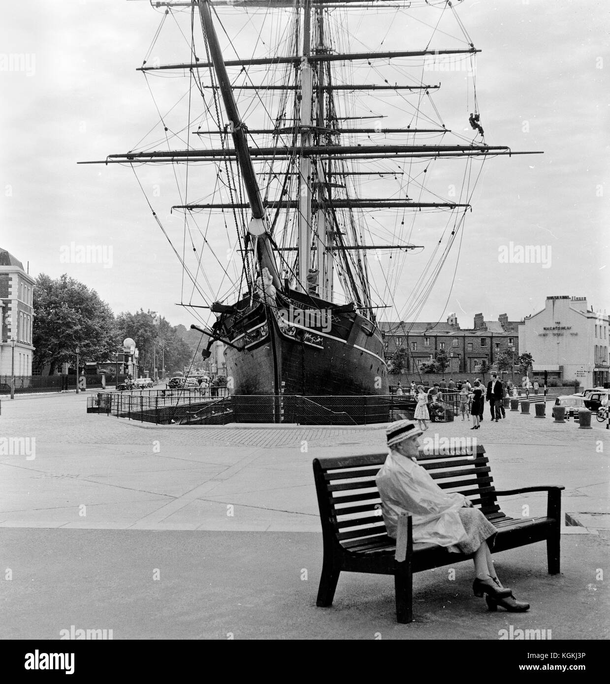 Museum Ship Cutty Sark im Trockendock in Greenwich im Jahr 1961 mit einer alten Dame sitzen auf einer Bank im Vordergrund. Stockfoto