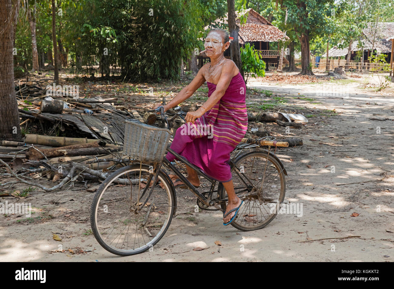 Alte burmesische Frau mit thanaka und Zigarre beim Radfahren im Karen Dorf in der Nähe von Hpa-an, Karen Staat/Karen Staat, Myanmar/Burma Stockfoto