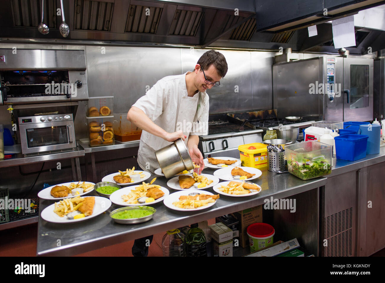 Gastronomie und Gastfreundschaft Arbeit in Großbritannien: ein Mann Vorbereitung Platten von Fisch und Chips in einem hotel restaurant Küche, Großbritannien Stockfoto