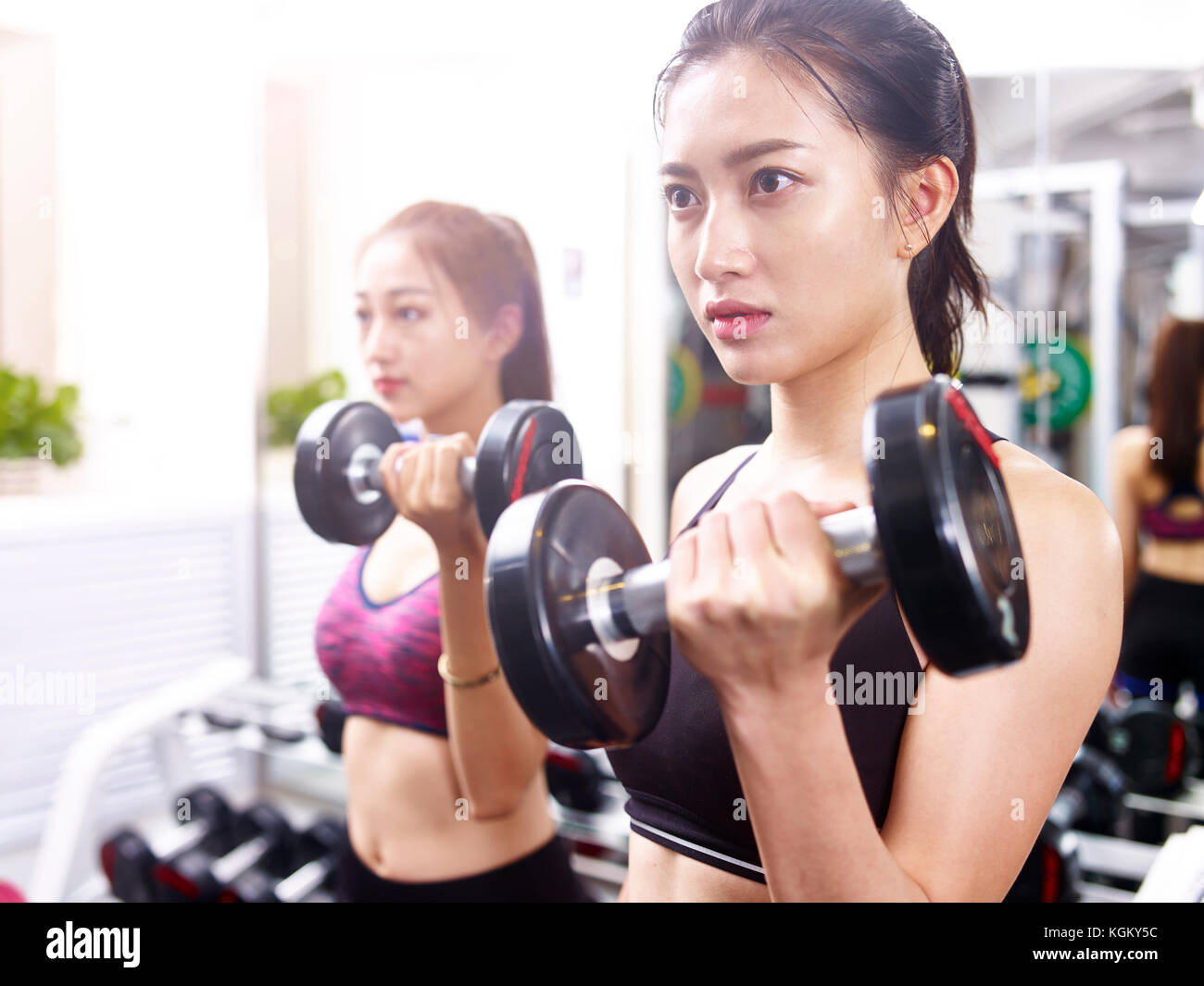 Zwei junge asiatische Frauen, trainieren Sie im Fitnessraum mit Hanteln. Stockfoto
