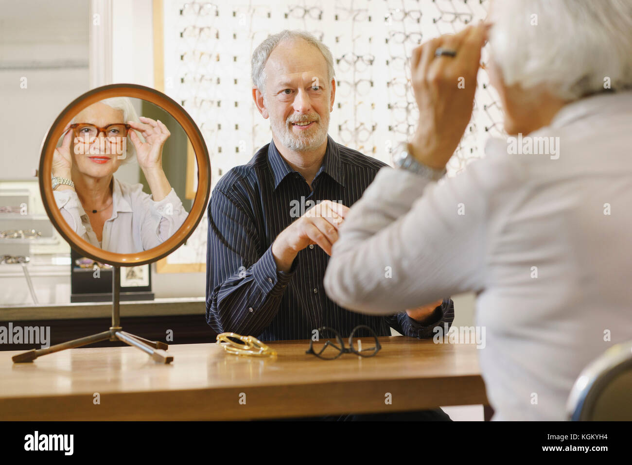 Optiker Unterstützung der älteren Frau, bei der Auswahl der Brillen bei Store Stockfoto