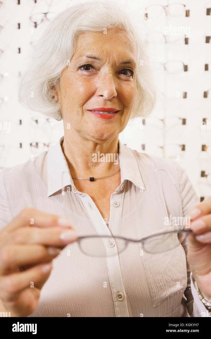 Portrait von lächelnden älteren Frau mit Brille bei Store Stockfoto
