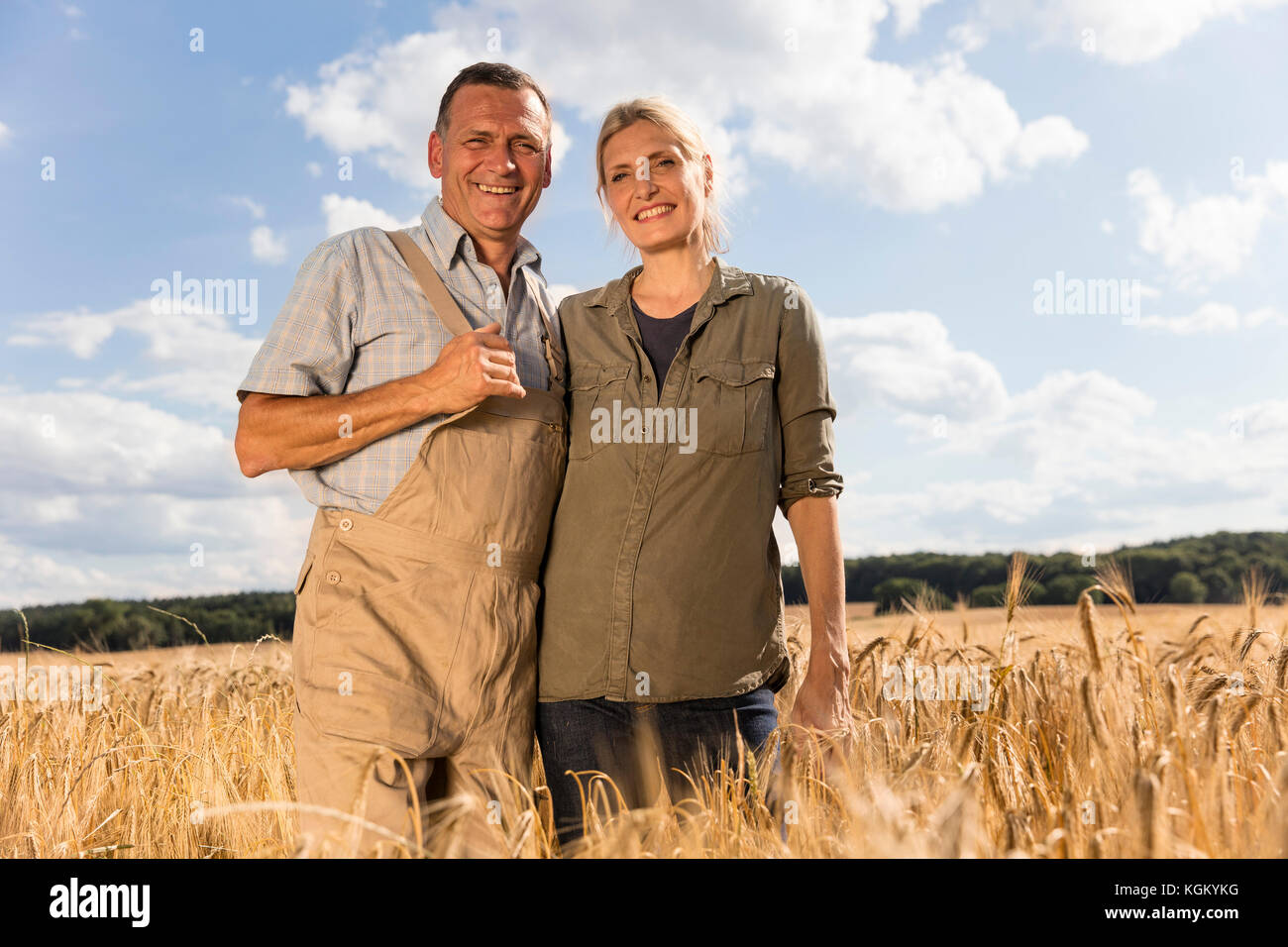 Low Angle Portrait von lächelnden Reifes Paar stehend an Farm gegen Sky Stockfoto
