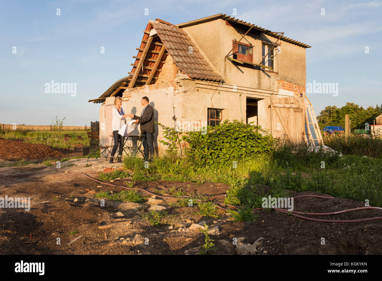 Immobilienmakler Händeschütteln mit Käufer während gegen Wohnhaus stehende Stockfoto