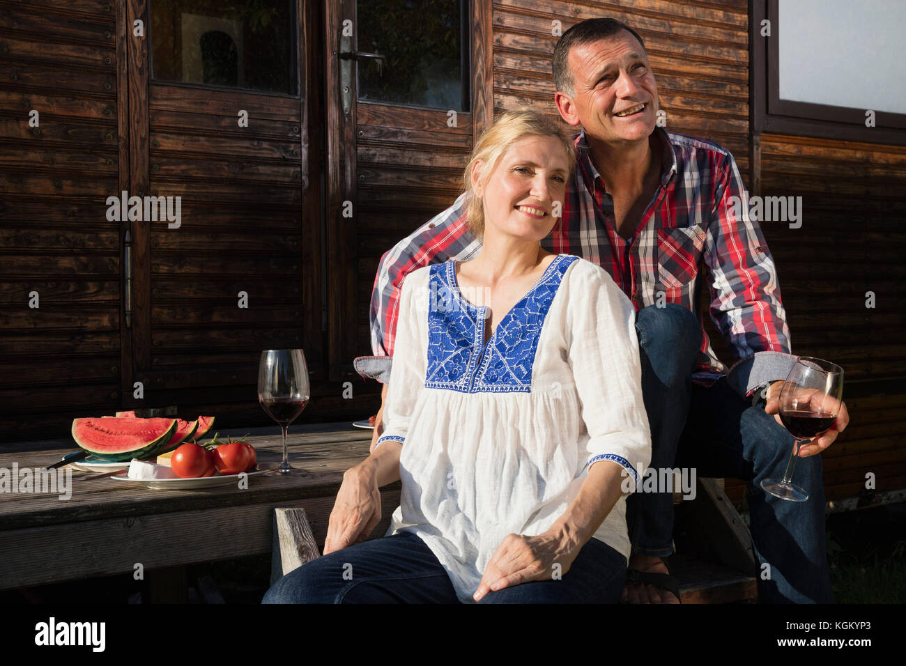 Lächelnd reifes Paar in Wein und Wassermelone, während sie sich außerhalb Bauernhaus Stockfoto