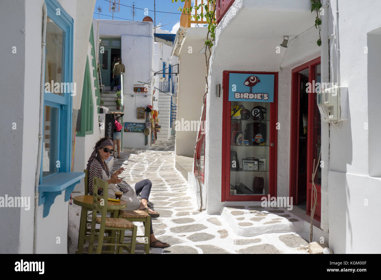 Junge griechische Frau sitzt vor ihr Shop, enge Gasse in der Altstadt von Naoussa, Paros, Kykladen, Griechenland, Mittelmeer, Europa Stockfoto