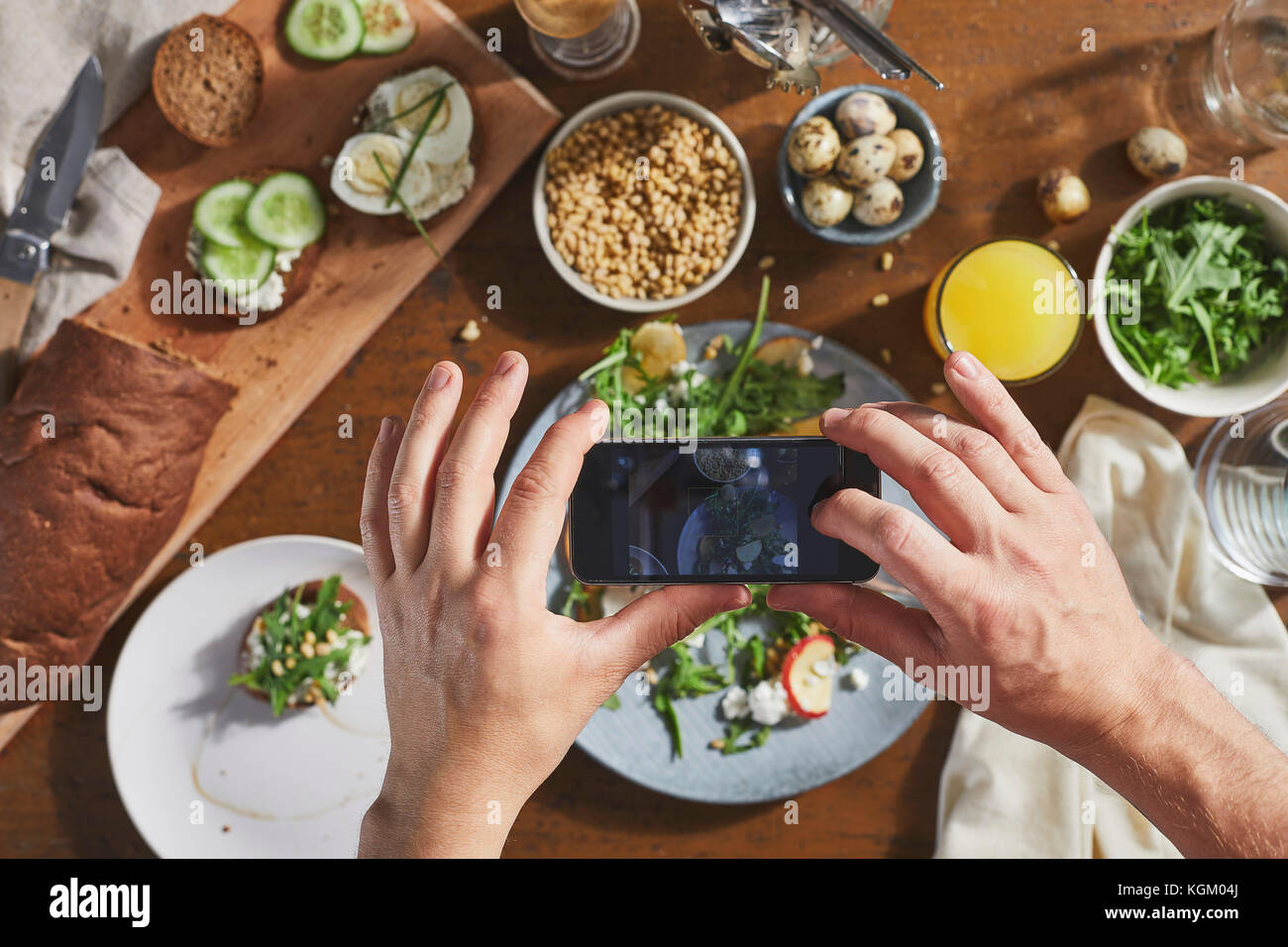 Zugeschnittenes Bild des Menschen fotografieren Essen am Tisch mit Handy Stockfoto