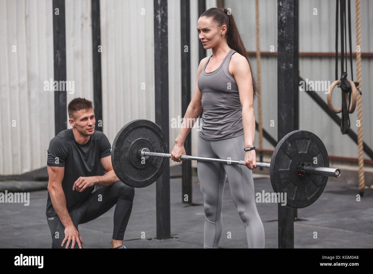Männliche Ausbilder an junge Frau crossfit Training im Fitnessstudio suchen Stockfoto