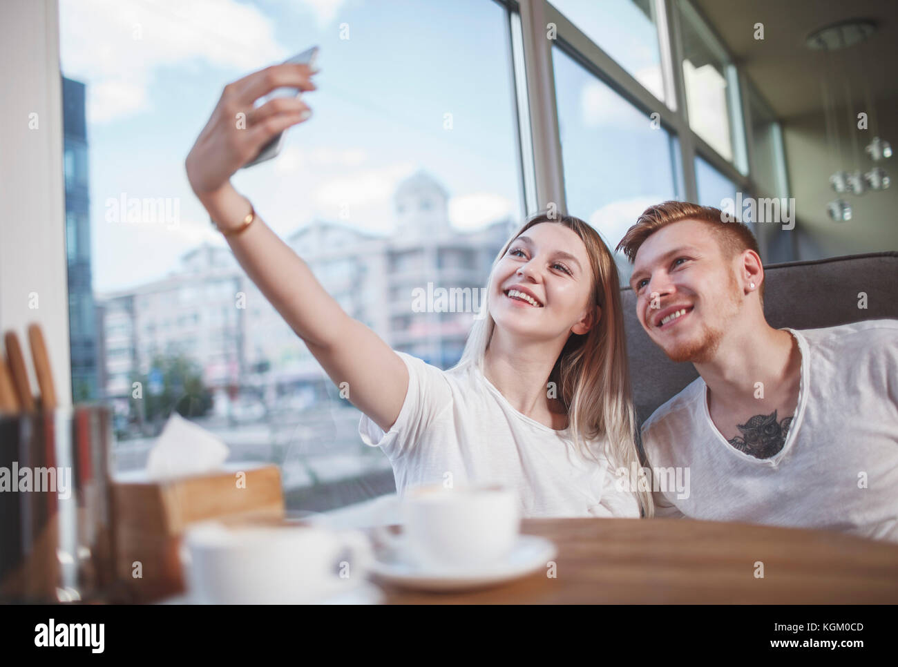 Glückliches junges Paar unter selfie mit Handy beim Sitzen im Restaurant Stockfoto
