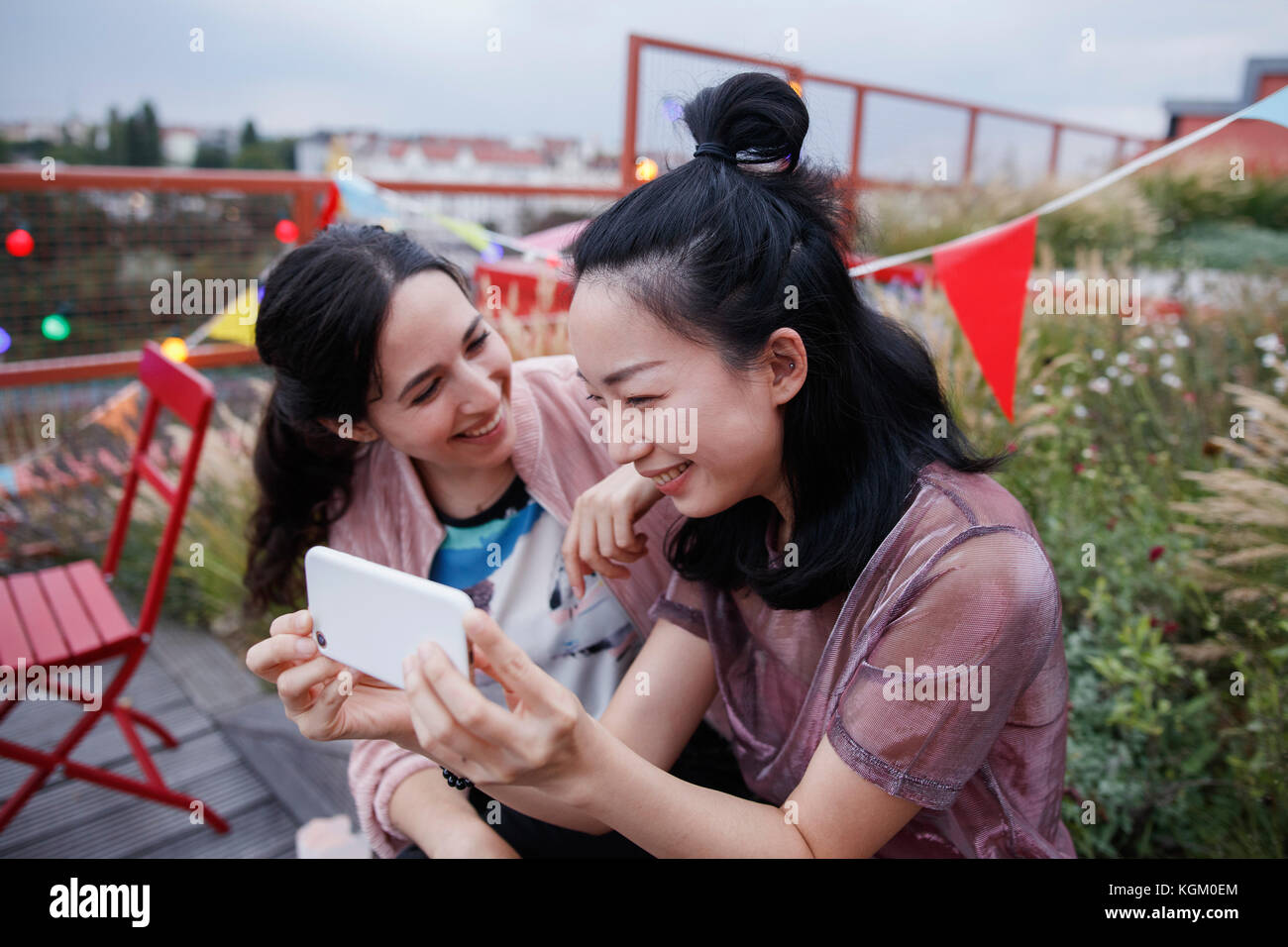 Glückliche Frau an der Freundin mit Smart Phone auf der Terrasse suchen Stockfoto